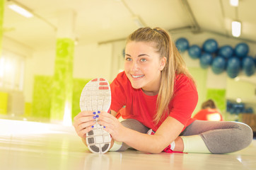 Attractive blonde caucasian girl is doing stretching at the gym
