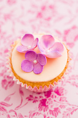 Single cupcake decorated with pink sugar flowers