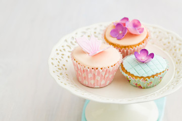 Cupcakes decorated with pink sugar flowers and a sugar butterfly