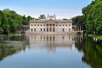 Fototapeta na wymiar Palace in Lazienki Park in Warsaw reflected in the water and surrounded by trees. Poland.