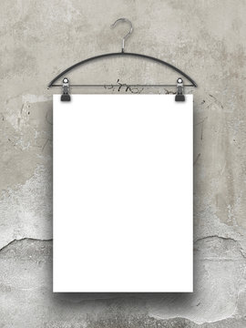 Close-up of one hanged paper sheet with clothes hanger on weathered concrete wall background