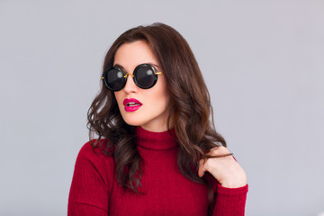 Attractive woman in glasses standing on grey background