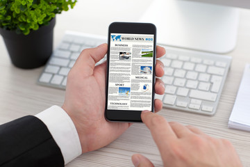 Businessman hands holding phone with world news site on screen