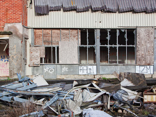 Debris and scrap metal strewn around the forecourt of an empty industrial building UK © pjhpix