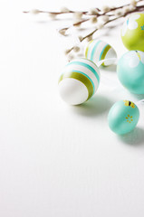 Easter eggs on a bright background with willow branches and copy space, selective focus.