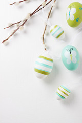 Colorful Easter eggs on a bright background with willow branches, top view