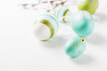 Colorful Easter eggs on a bright background with willow branches and copy space, selective focus.