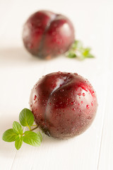 Frisch gewaschene Pflaumen liegen auf einem Holzbrett.