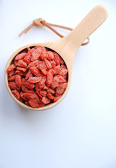 healthy dried goji berries in a wooden cup in white background