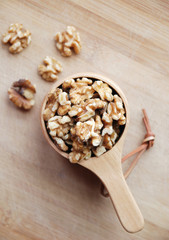 whole walnuts in a wooden cup on bamboo board