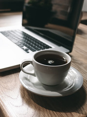Fototapeta na wymiar Cup of Black Coffee Beside Laptop