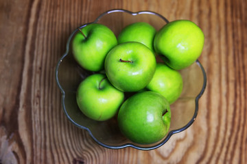 green apple in a glass bowl wooden background