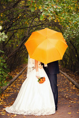 newlyweds and orange umbrella
