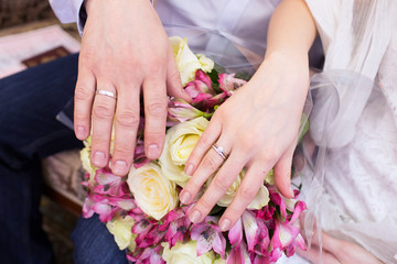 Hands of the groom and bride with rings and bridal bouquet