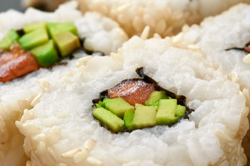Sushi rolls with avocado, salmon and sesame seeds.