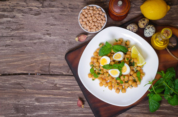 Mediterranean cuisine. Dish of chickpeas with mint, olive oil and lemon sauce on a wooden background