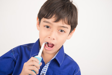 Little boy using electric toothbrushes on white background