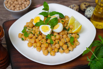 Mediterranean cuisine. Dish of chickpeas with mint, olive oil and lemon sauce on a wooden background