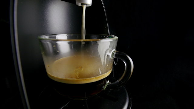 Making cappuccino in glass transparent sided coffee cup.