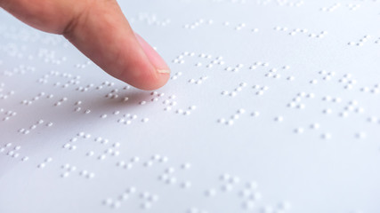 Finger read braille text in white paper. - obrazy, fototapety, plakaty
