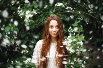 Young Woman among Spring Flowers Outdoors