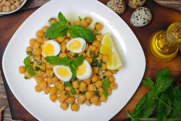Mediterranean cuisine. Dish of chickpeas with mint, olive oil and lemon sauce on a wooden background