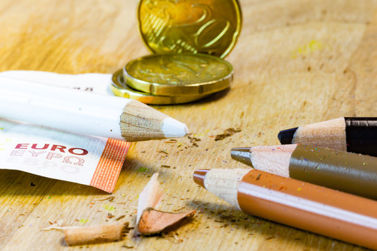A white pencil surrounded by money is facing poor black and brown pencils in this racism and money inequality pencil concept.