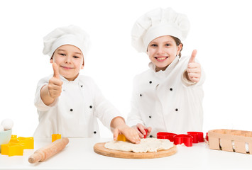 two little chefs cutting dough with thumbs up