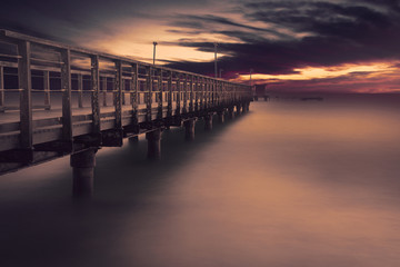 Fototapeta na wymiar Long wooden bridge on the beach