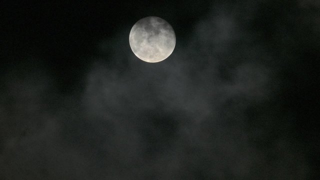 Full moon among moving clouds