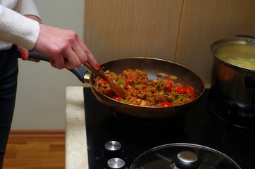 A woman is cooking mince with vegetables closeup