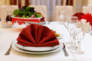 Table in a restaurant with wine glasses, red napkins and cutlery