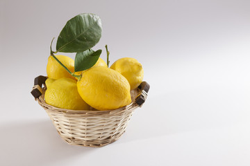 Lemons overflowing in basket arranged over white background