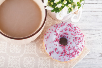 Three donut, a cup of coffee and willow on a white table