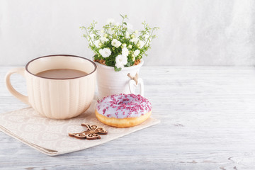 Three donut, a cup of coffee and willow on a white table