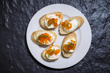 White plate of sandwiches with egg and red caviar. View from above.
