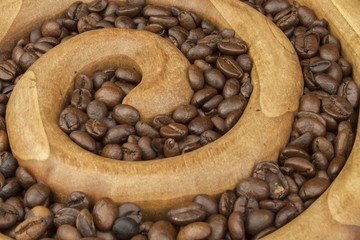 Roasted coffee beans in a wooden spiral on the canvas background. Fresh roasted coffee. Preparing for brewing coffee.
