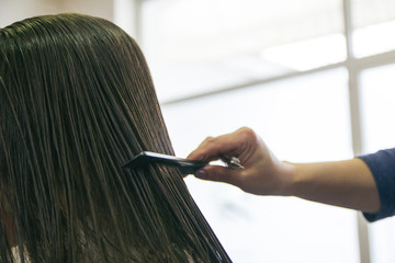 Hand of a hairdresser combing the hair of a girl in a hairdressing