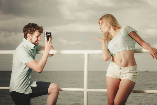 Young couple in love is taking photos on sea pier.