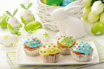 Easter decoration - colored eggs, muffins and bunny on wooden background.