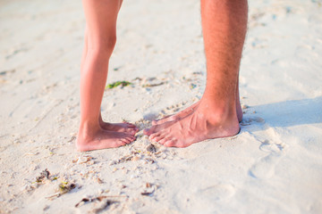 Fototapeta na wymiar Closeup kids and adult feet on white sandy beach