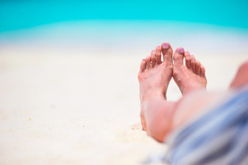 Young woman sunbathing on white beach. Legs.