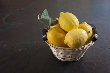 Fresh lemons basket on dark stone table