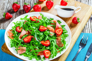 strawberry, arugula, prosciutto salad on a white dish