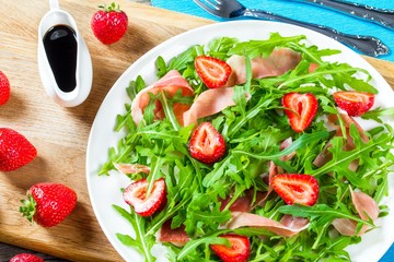 strawberry, arugula, prosciutto salad on a white dish