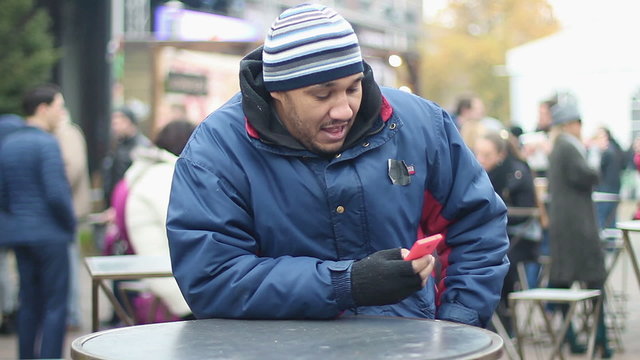 Optimistic migrant having fun at street festival, taking phone out of pocket