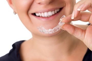 Woman with perfect teeth holding invisible braces