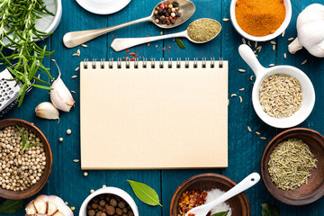 culinary background and recipe book with various spices on wooden table