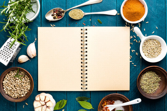 culinary background and recipe book with various spices on wooden table