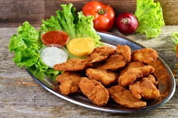 Fried chicken fillets on a wooden background.